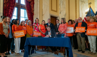 Gov McKee signing law in front of Moms Demand Action