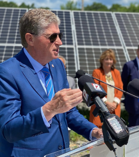 Gov McKee speaking in front of solar panel array