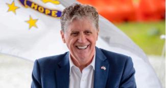 Governor sitting in front of Rhode Island Flag